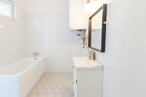 A bathroom with a white bathtub, a sink, and a mirror.