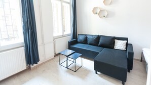 Una sala moderna con un sofá negro, una mesita negra y un radiador blanco.