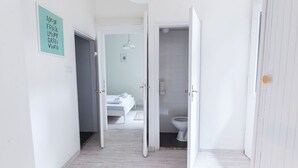 Un pasillo con una cama, un inodoro y una puerta que da a un baño.