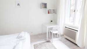 Un dormitorio minimalista con cama, escritorio y radiador.