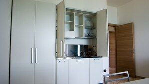 Een keuken met witte kastjes, een aanrecht en een houten deur.