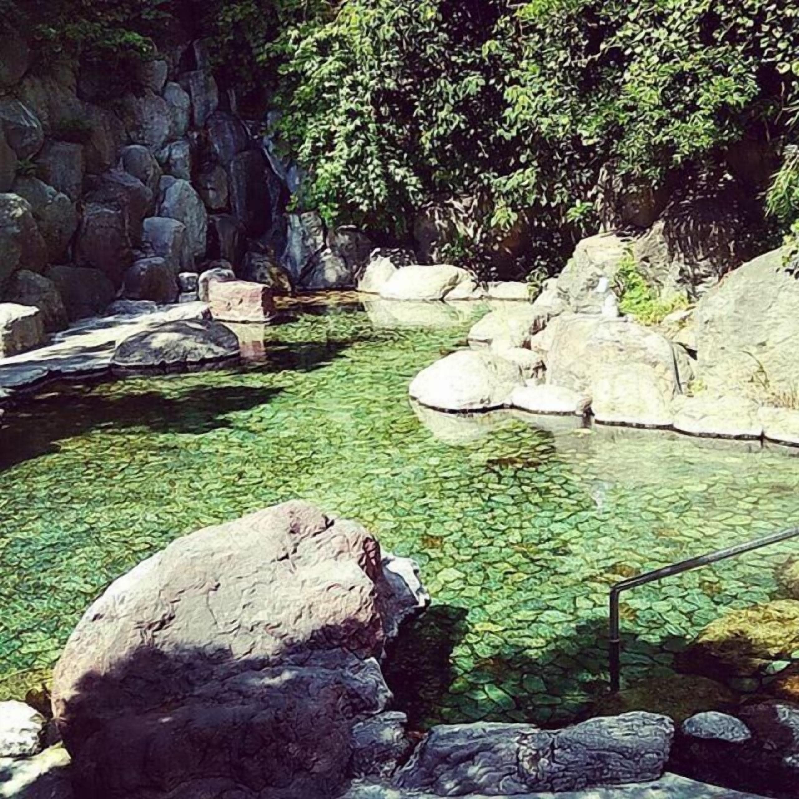 A clear water feature with rocks and a wooden bench.