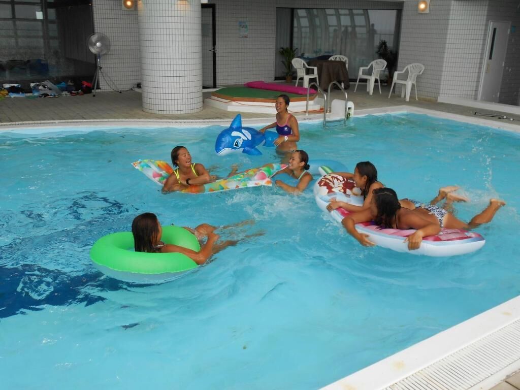 Una piscina interior con gente flotando en círculos inflables.