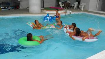 Una piscina interior con gente flotando en círculos inflables.