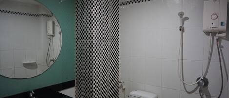 A bathroom with a round mirror, a sink, a toilet, and a shower with a control panel.