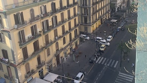 A street view of a city with multi-story buildings, a crosswalk, and parked vehicles. - Di Palma Suite (Naples)