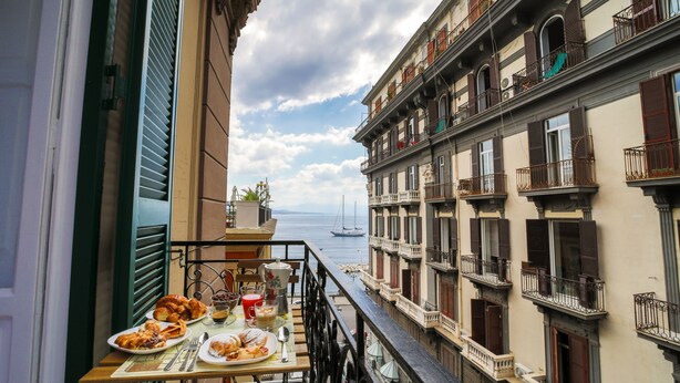 A balcony with a table set for breakfast overlooking a marina. - Di Palma Suite (Naples)