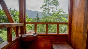 A wooden balcony with a view of lush greenery and mountains.