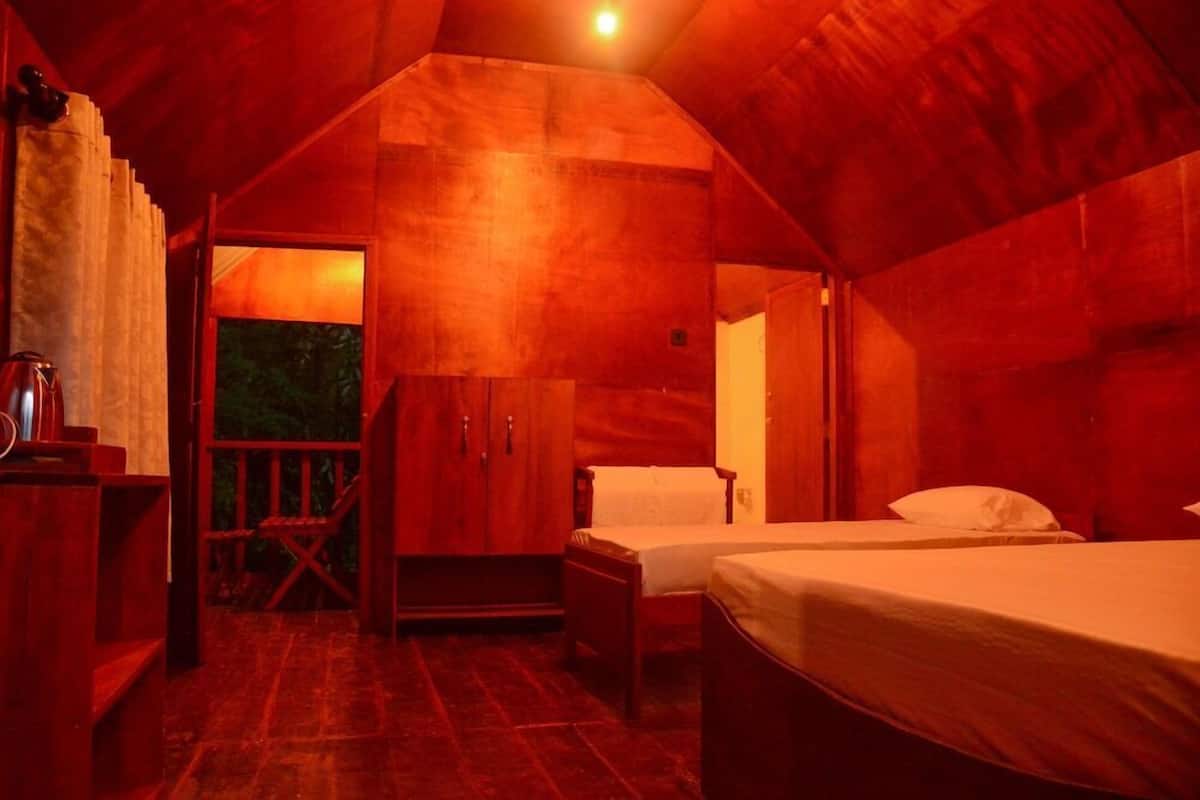 A cozy cabin with a wooden interior, a bed, a chair, and a small table.