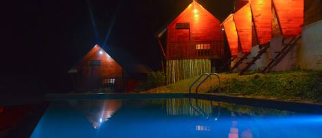 Ein Schwimmbecken mit Holzbauten im Hintergrund.