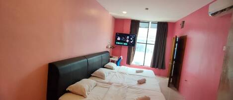 Ein Hotelzimmer mit einem großen Bett, einem flachbildfernseher an der Wand und einem Fenster mit Vorhängen.