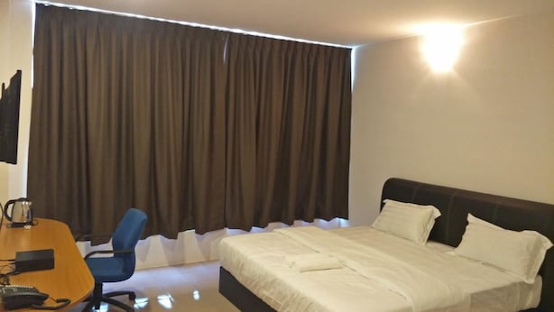 A hotel room with a bed, a desk with a chair, and a large window with curtains. - Anderson Hotel (Ipoh)