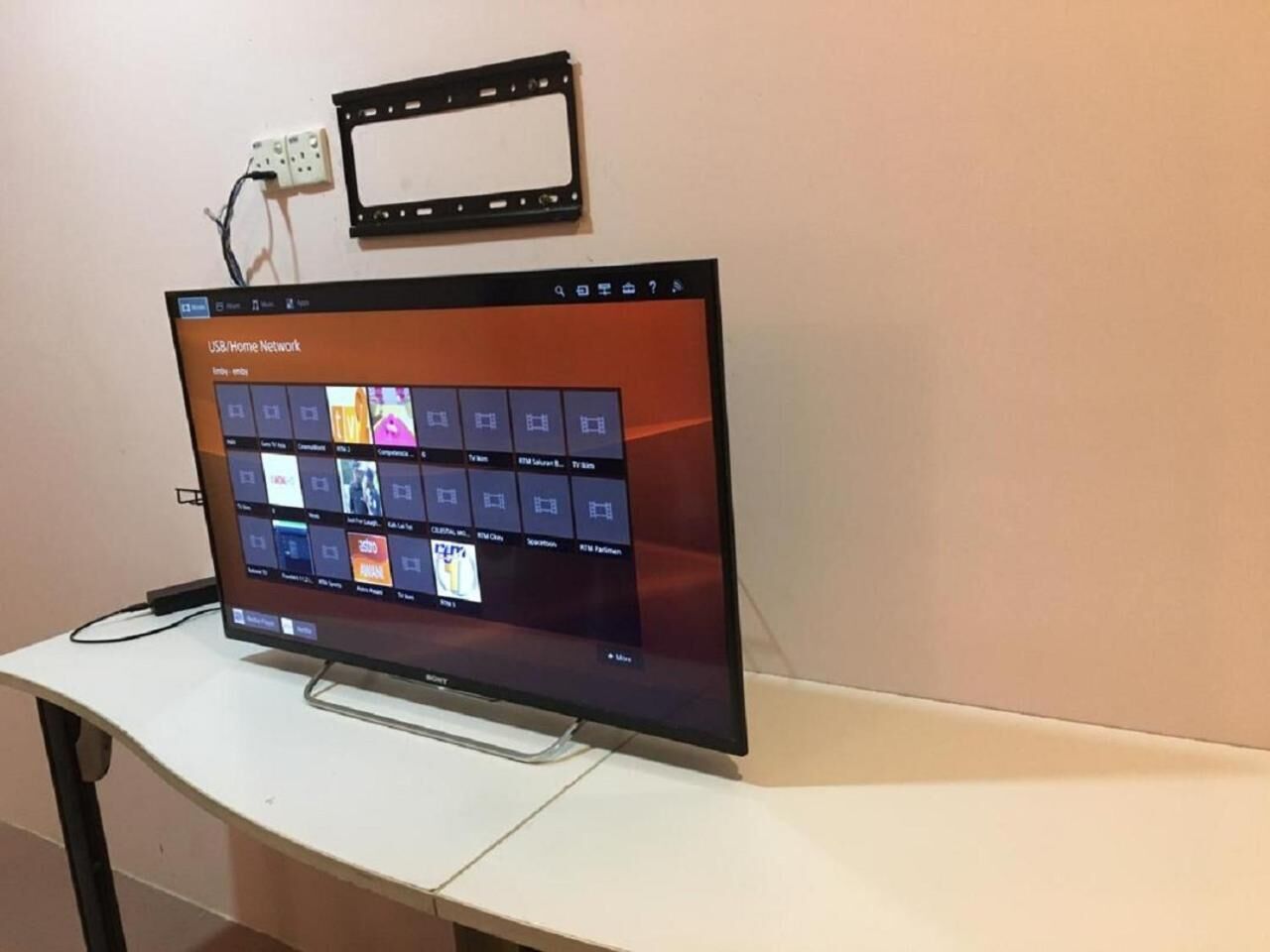 A flat-screen TV on a white desk with a USB/Home Network interface displayed.