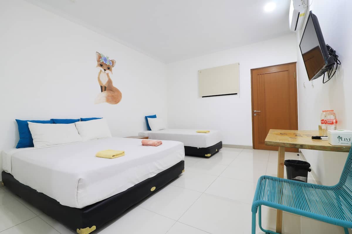 A hotel room with two beds, a TV, a desk with a chair, and a wall-mounted air conditioner.