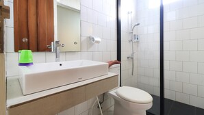 Un baño con lavamanos, espejo y retrete blancos.
