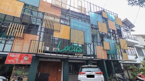 Un edificio con un letrero que dice "Locus Rooms" y un coche blanco estacionado al frente.
