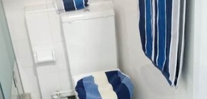 Un baño con una bañera blanca, una toalla azul y blanca a rayas y un inodoro blanco.