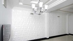 A room with a textured white wall, a black and white tiled floor, and a chandelier with multiple light fixtures. - Capital & County Apartment Ikate (Lekki)