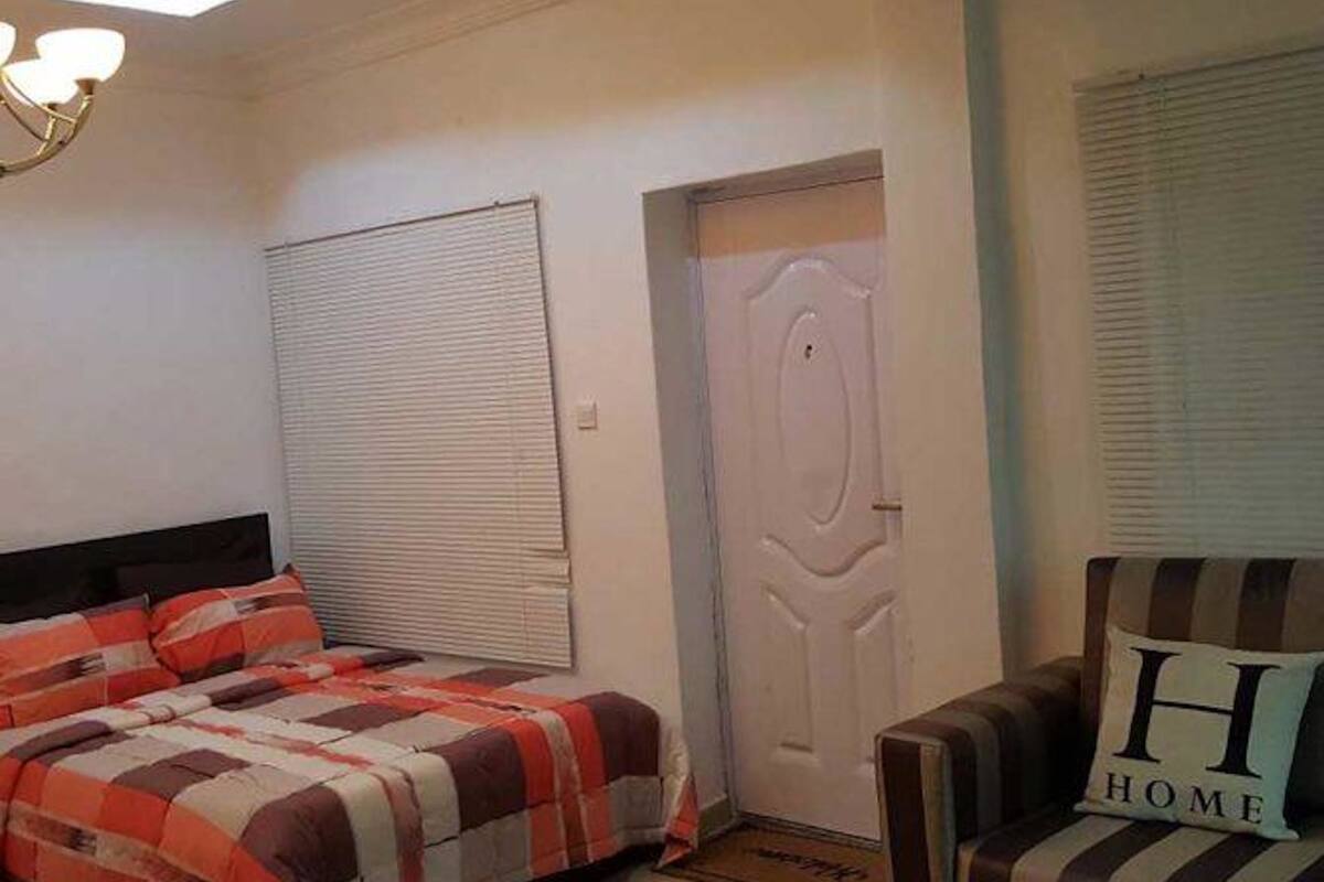 A bedroom with a bed, a door, and a chair with a pillow.