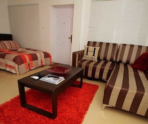 Una sala de estar con un sofá a rayas, un tapete rojo y una mesa de centro.