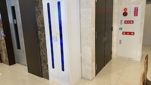 An elevator with a blue stripe, a fire alarm panel, and a wheelchair accessibility sign. - Toyoko Inn Shin Osaka Higashi Mikuni Station (Osaka)
