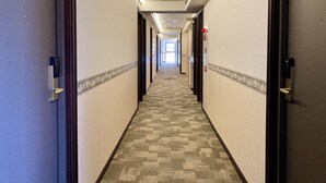 A hotel hallway with carpeted floors, doors on both sides, and a sign indicating a VOD room. - Toyoko Inn Shin Osaka Higashi Mikuni Station (Osaka)