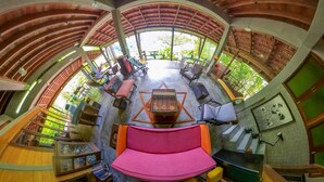 A circular room with a central table, multiple seating areas, and a view of greenery outside. - Spyder Hill (Seremban)