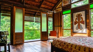 A wooden room with a bed, a chair, and a fan. - Spyder Hill (Seremban)