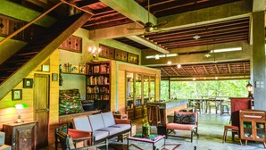 A spacious indoor area with a staircase, seating arrangements, and a bookshelf. - Spyder Hill (Seremban)