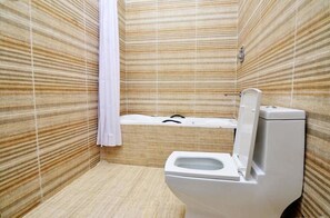 A bathroom with a toilet, a bathtub, and a shower curtain. - Madiba Court (Lekki)