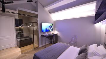 Quarto moderno com cama, escrivaninha, televisão e closet espaçoso.