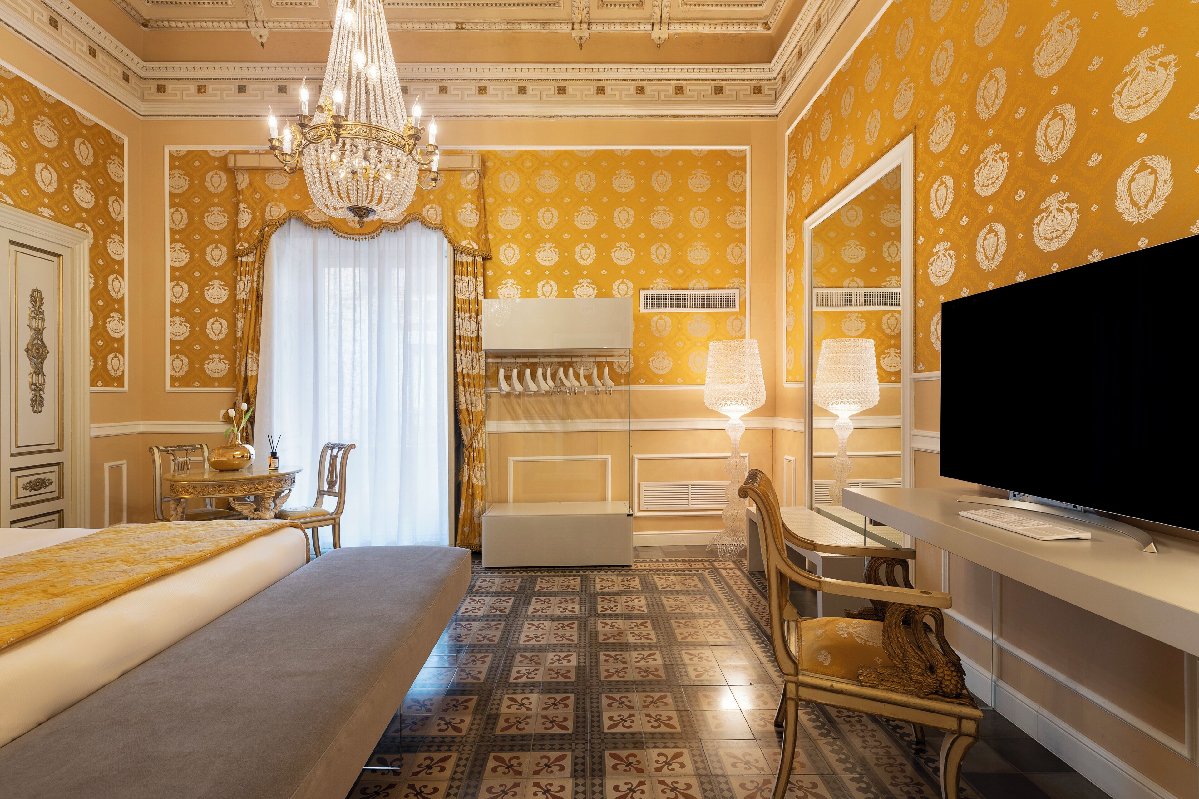 Una lussuosa camera d'albergo con un letto grande, una scrivania con un computer, una televisione e un lampadario.