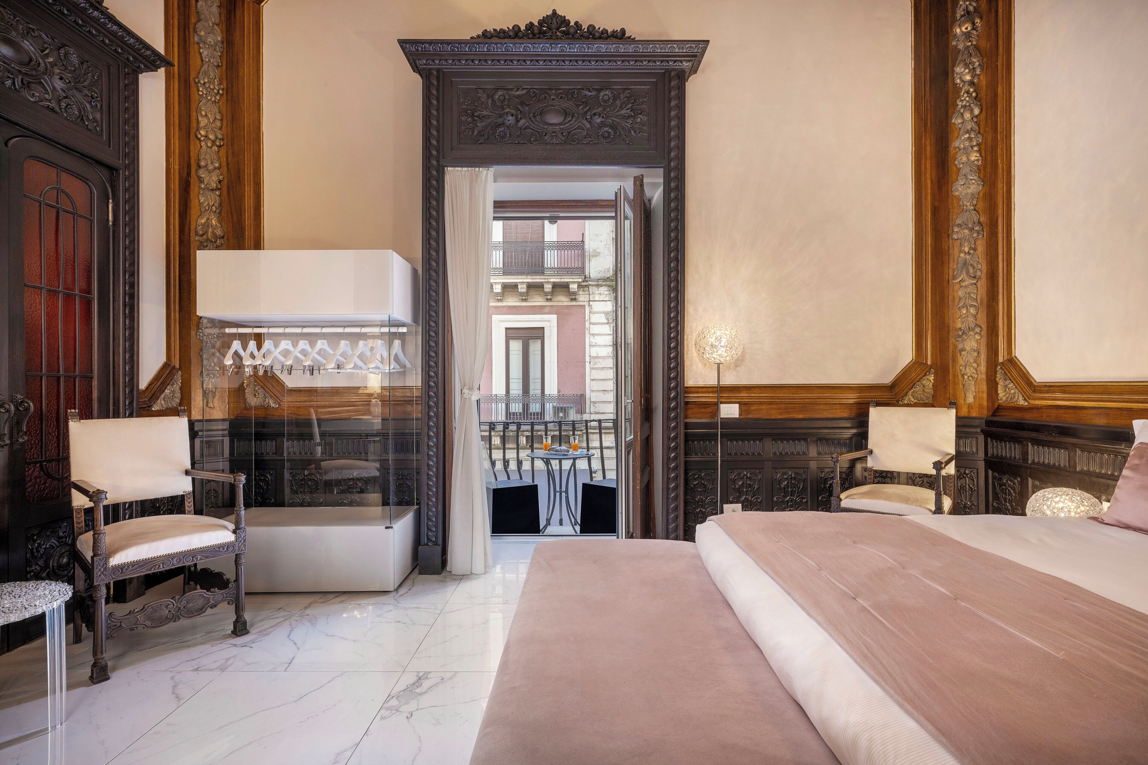 Une chambre d’hôtel avec un grand lit, deux chaises, une table et un balcon avec vue.
