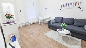 A modern living room with a grey sofa, a white coffee table, and a small white table with a lamp. A decorative feather wall art is visible. - Classic Ernesto near Opera (Budapest)