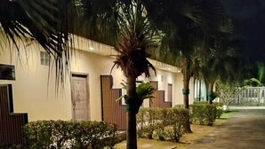 A pathway leading to a building with a gated entrance, surrounded by well-maintained bushes and palm trees, under nighttime lighting. - Journey Residence Phuket  (Choeng Thale)