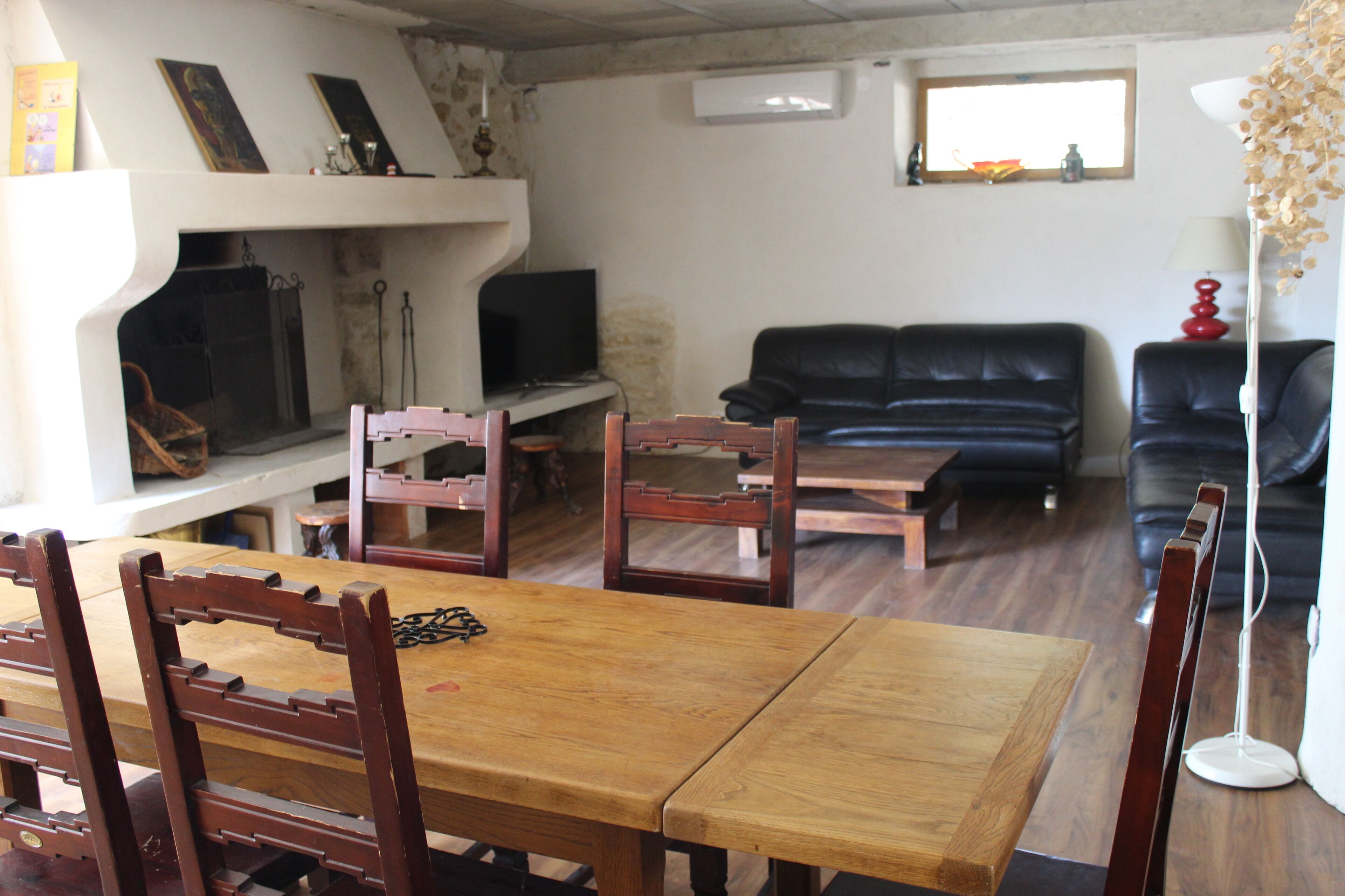 A living room with a fireplace, a sofa, a dining table, and chairs.