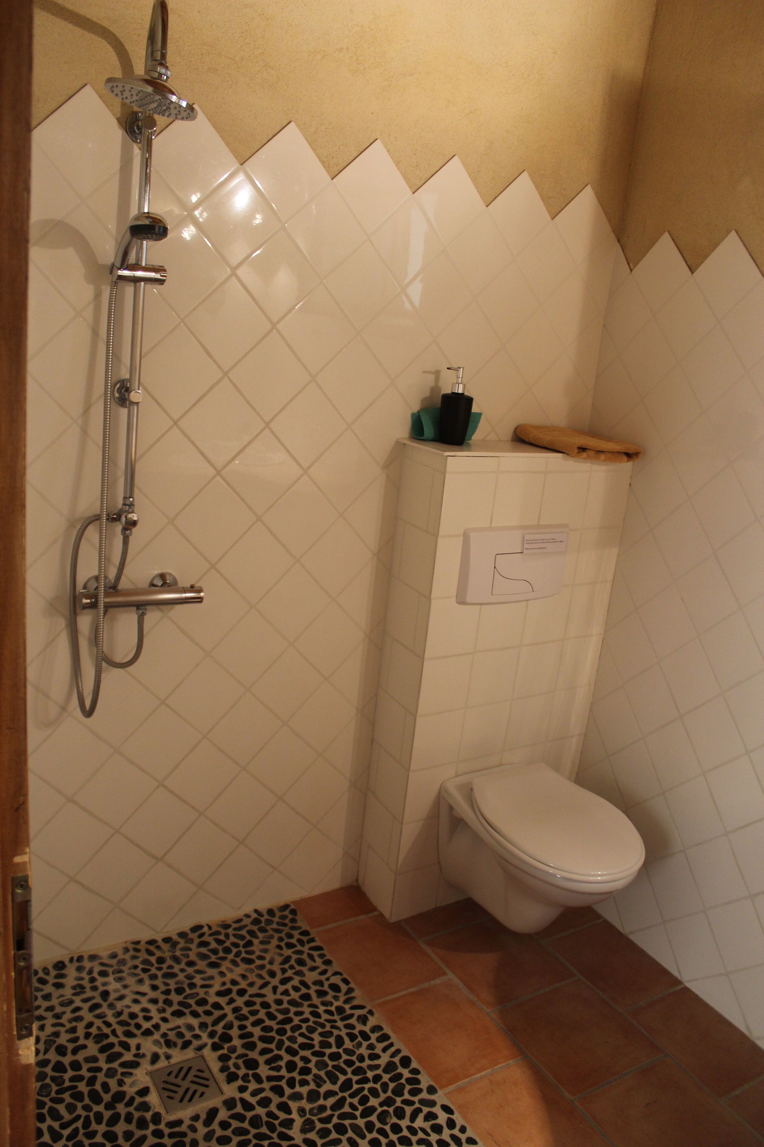 Een kleine badkamer met een douche, toilet en een betegelde vloer.