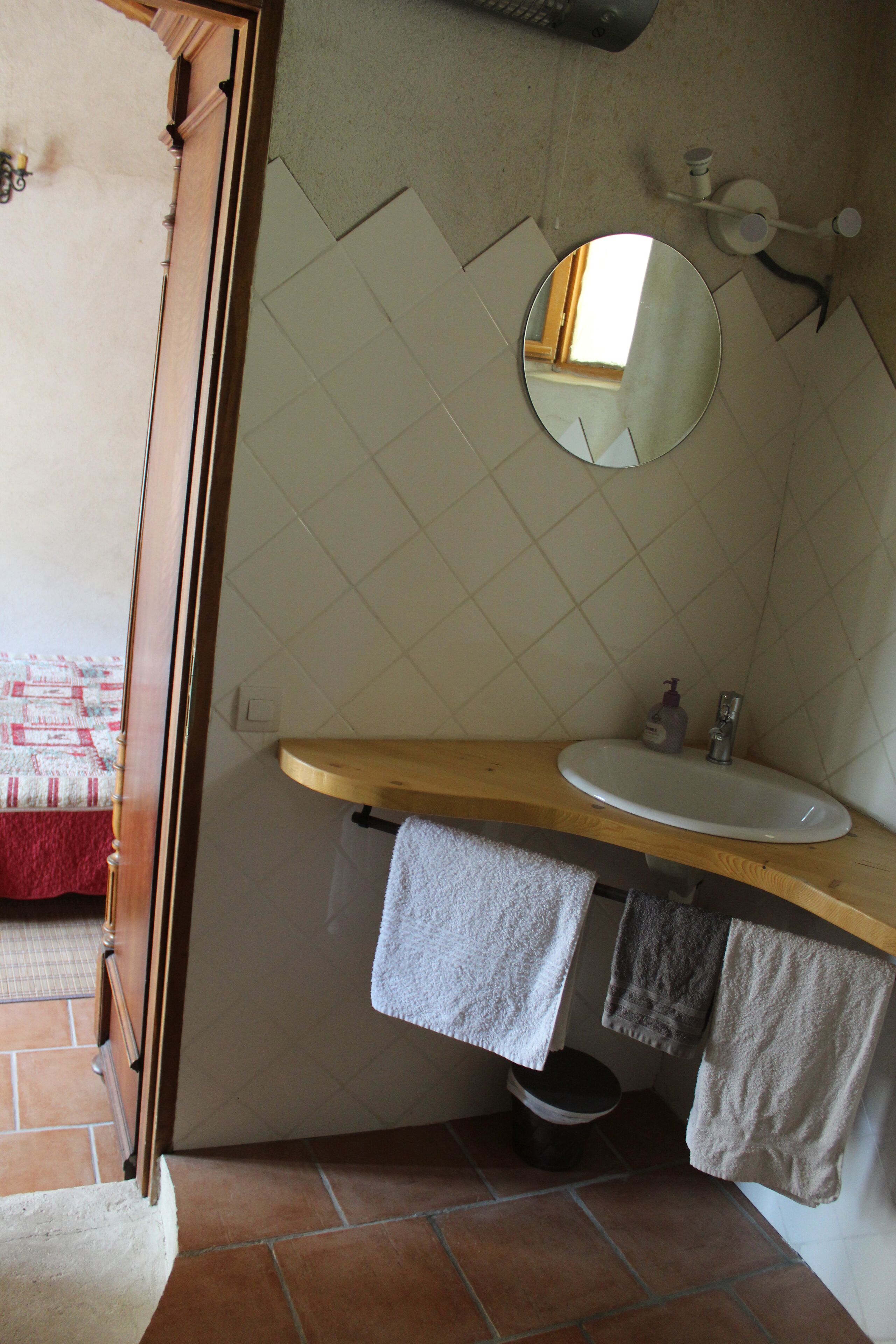 Un baño con tocador de madera, un lavamanos blanco, un espejo y un perchero para toallas.