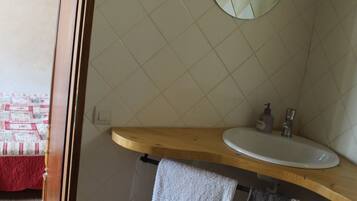 Un baño con tocador de madera, un lavamanos blanco, un espejo y un perchero para toallas.