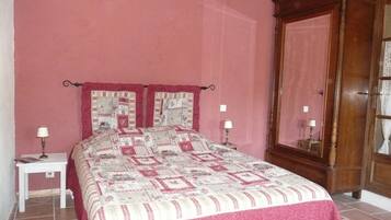 Un dormitorio con una cama grande, dos mesitas de noche con lámparas, un armario de madera y una pared rosa.