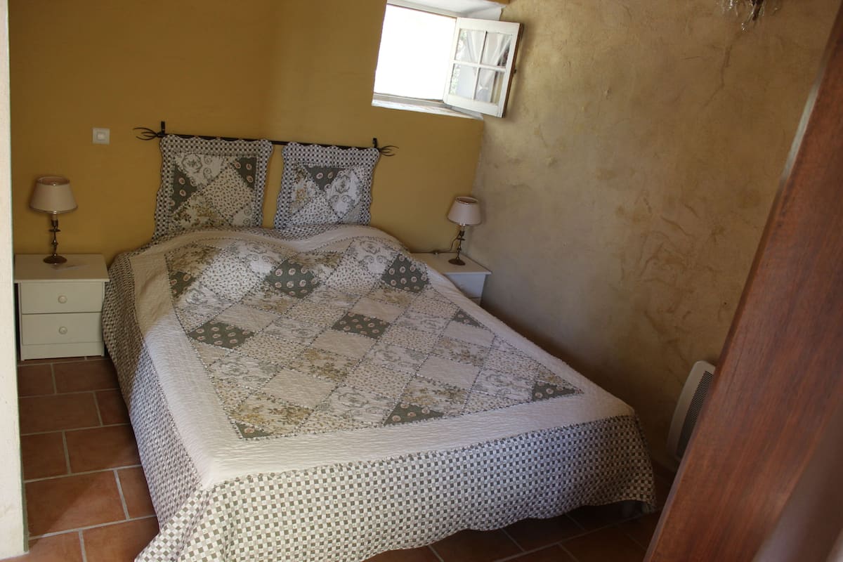 A bedroom with a bed, two nightstands, a window, and a door.
