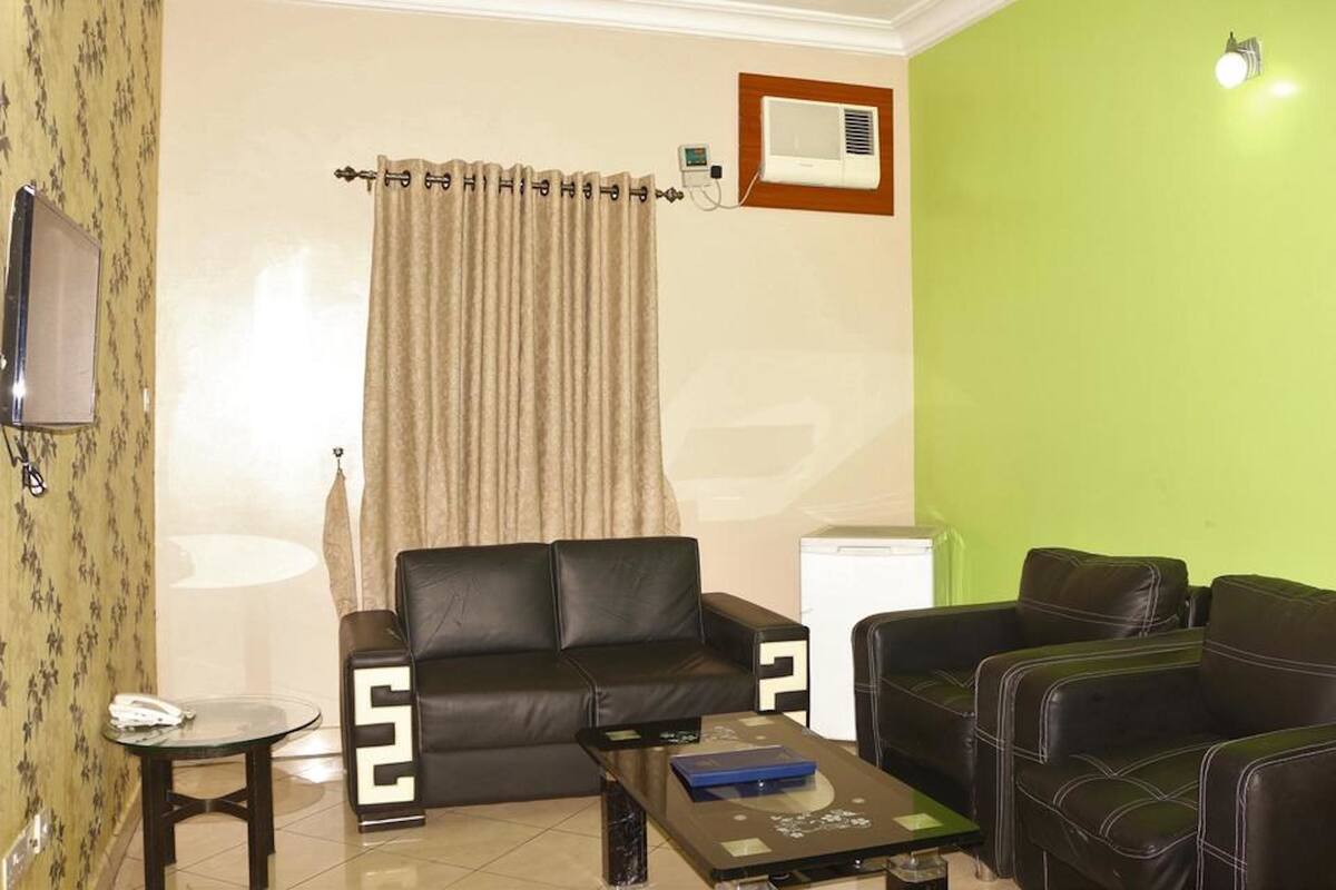 Una sala de estar con un sofá, una mesa de centro, una mesita, un televisor y un aire acondicionado de pared.