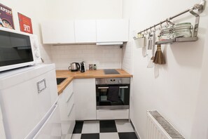 A compact kitchen with white cabinets, a microwave, an oven, and a coffee maker. - Cozy Ernesto II (Budapest)