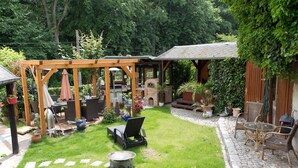 A covered patio area with outdoor furniture, a grill, and potted plants. - Domizil Adler (Dresden)