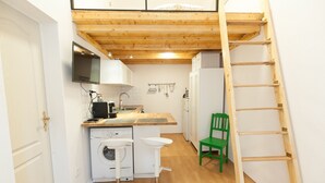 Cocina compacta con lavadora, lavaplatos, microondas y una escalera de madera.