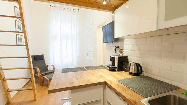 Una cocina funcional con encimera de madera, estufa integrada, lavabo y una silla.