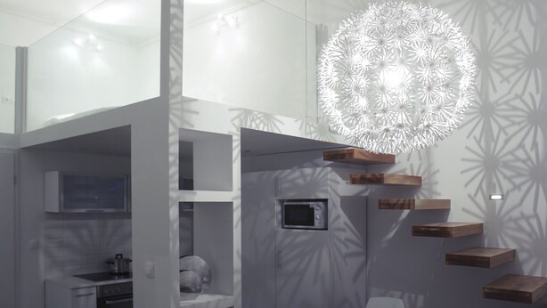 Een moderne keuken met inbouwapparatuur, een magnetron en een hangende lamp.