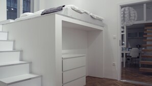 Een moderne kamer met een stapelbed, een witte inloopkast en een houten visgraatvloer.