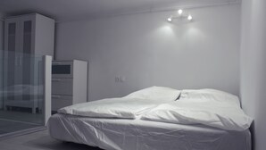 Een moderne slaapkamer met een bed, een kledingkast en een glazen deur naar een balkon.
