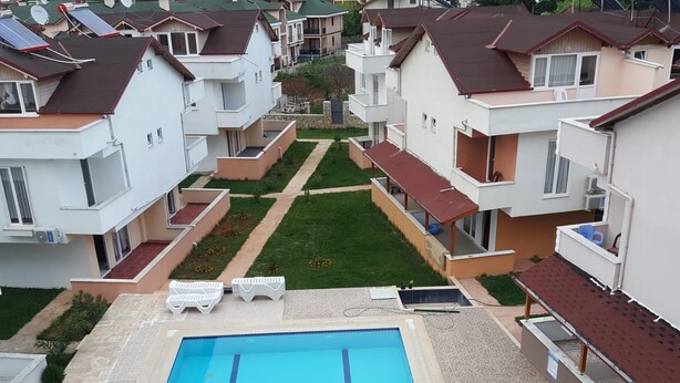 Un complexe résidentiel doté d’une piscine centrale, de nombreux balcons et d’une pelouse bien entretenue.